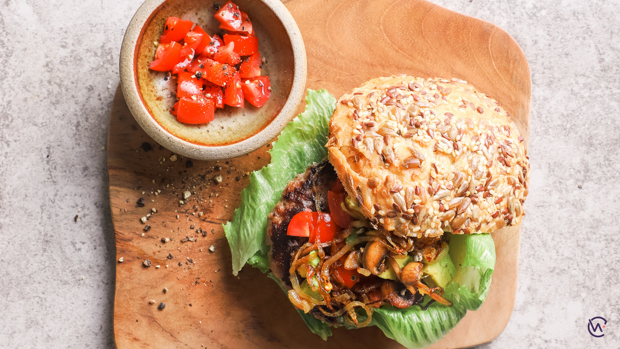 A burger with a wholegrain bun and side of tomatoes